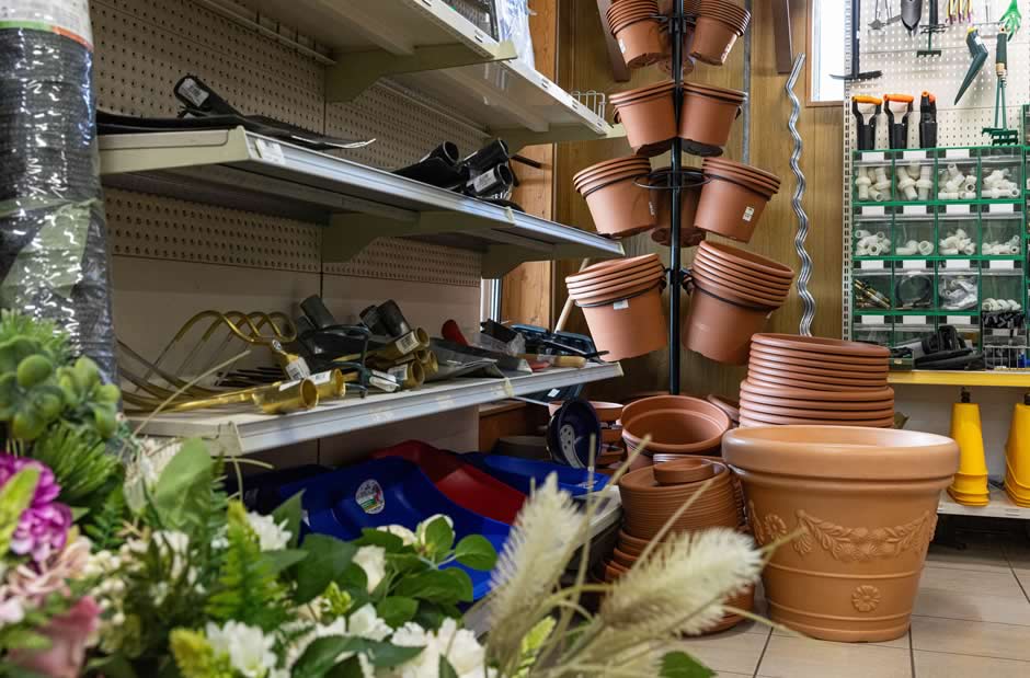 Scaffali reparto giardinaggio con vasi in terracotta di varie dimensioni e attrezzi manuali da lavoro